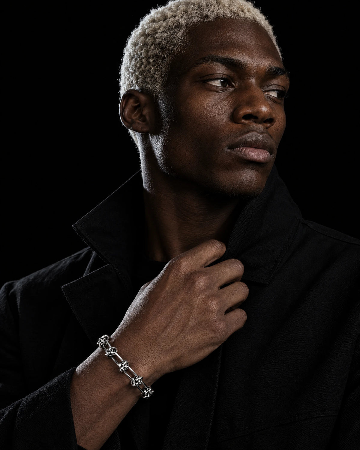 Nemesis jewelry worn by a model in black streetwear.