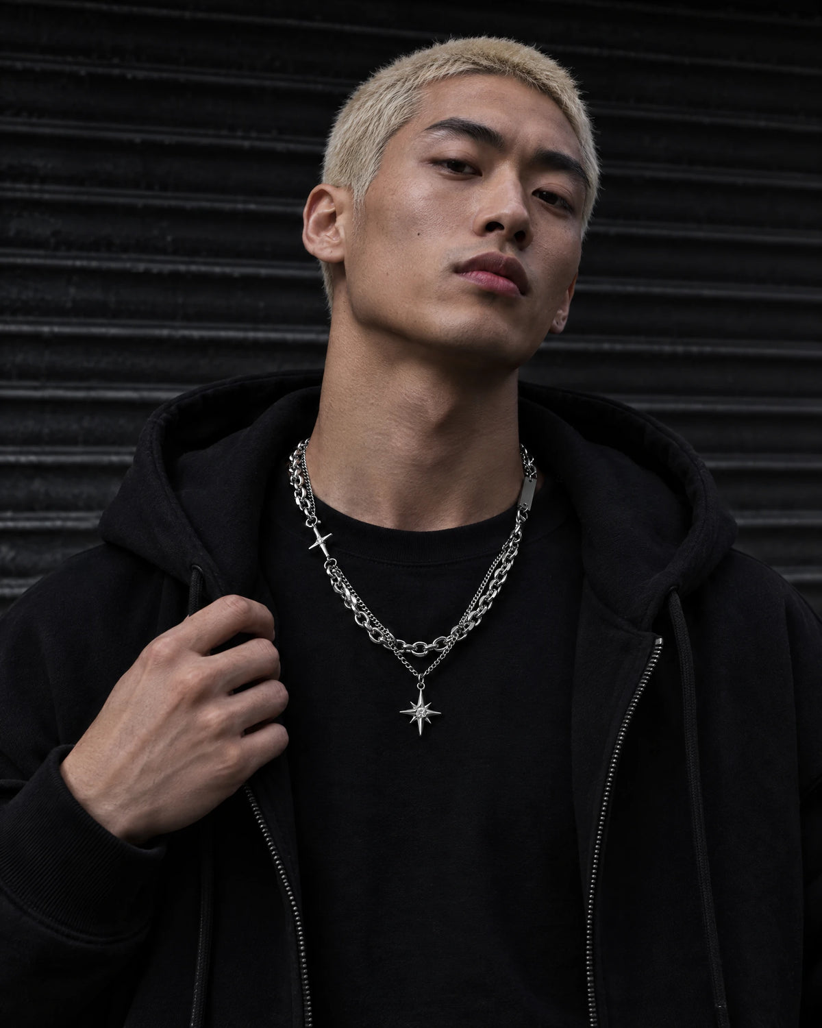 Nyx jewelry worn by a model in black streetwear.