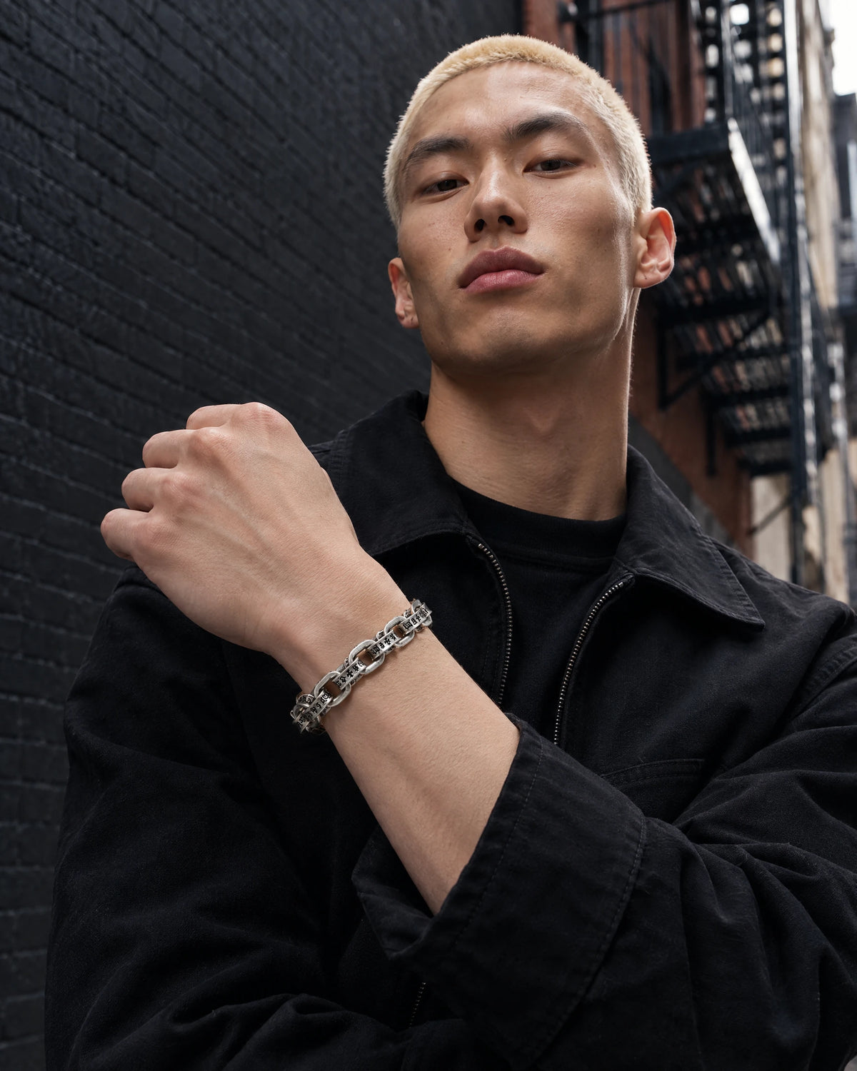Pluto jewelry worn by a model in black streetwear.