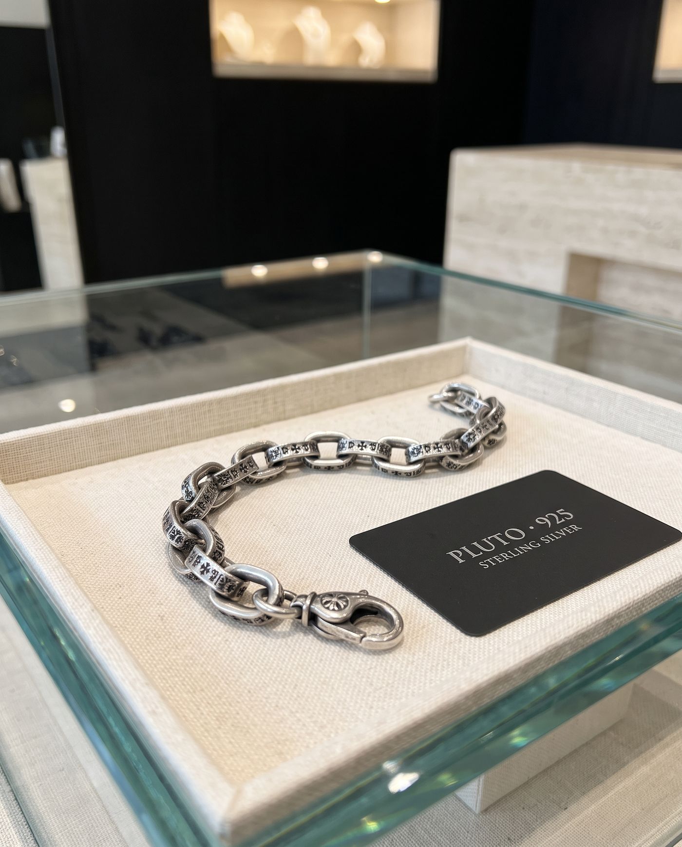 Pluto sterling silver chain bracelet on a linen tray