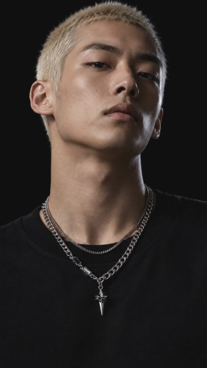 Astraea necklace showcased by an adult male model in black crew-neck streetwear, with a moving close-up of the silver design.