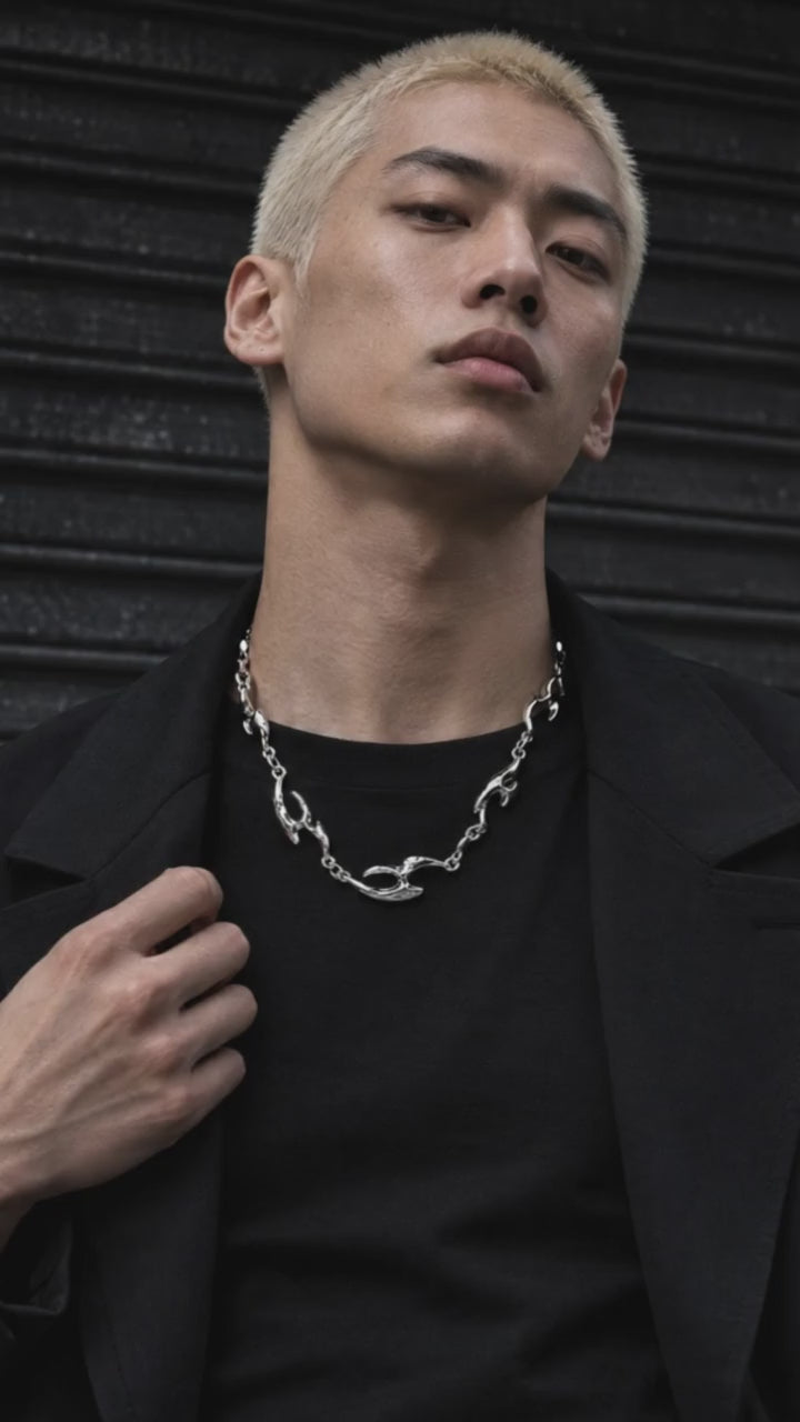 Erebus necklace showcased by an adult male model in black crew-neck streetwear, with a moving close-up of the silver design.