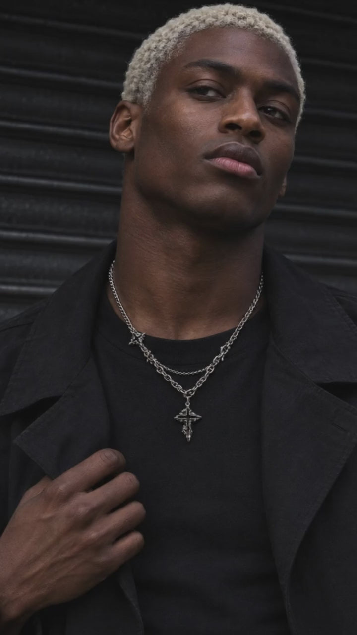 Hypnos necklace showcased by an adult male model in black crew-neck streetwear, with a moving close-up of the silver design.