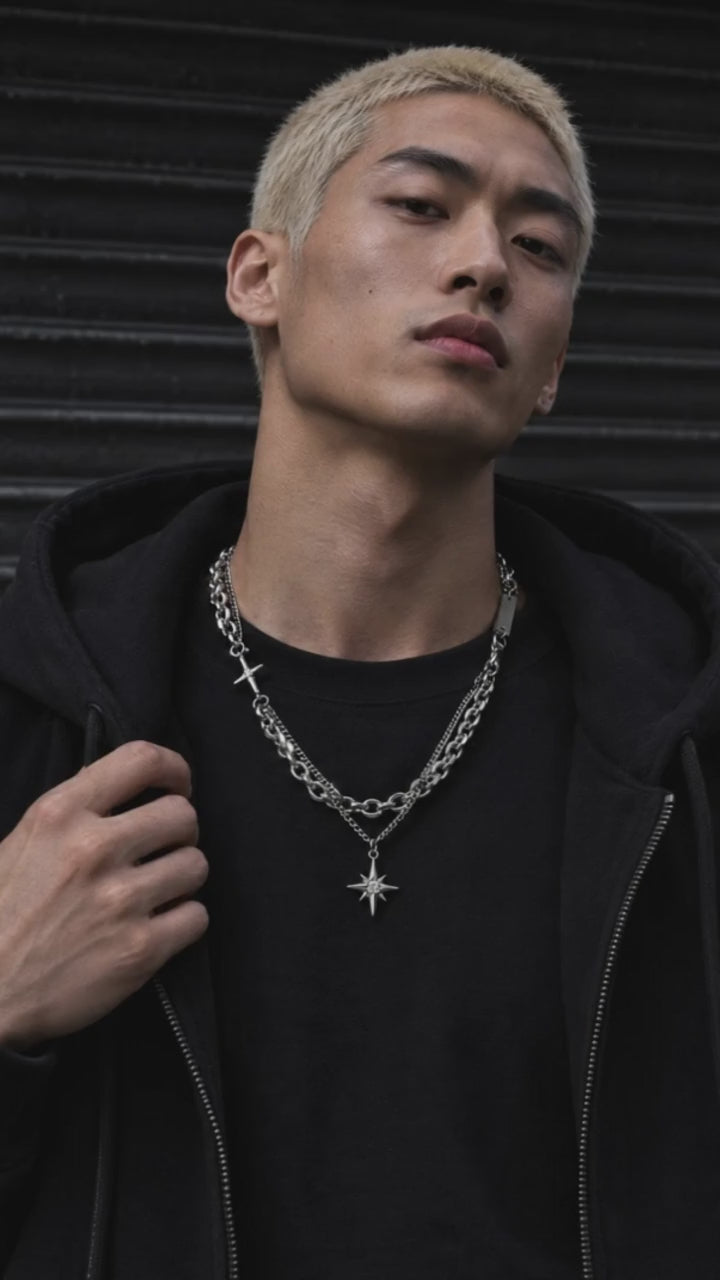 Nyx necklace showcased by an adult male model in black crew-neck streetwear, with a moving close-up of the silver design.